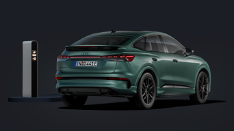 Der Q4 Sportback e-tron von schräg hinten auf dunklem Hintergrund, links daneben eine Ladesäule.