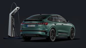Der Q4 Sportback e-tron von schräg hinten auf dunklem Hintergrund, flankiert von einer modernen Ladesäule.
