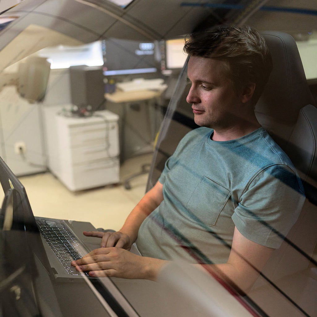 Jan Totz is sitting in the passenger seat of an Audi, looking at a laptop on his lap. You can see him through the windshield