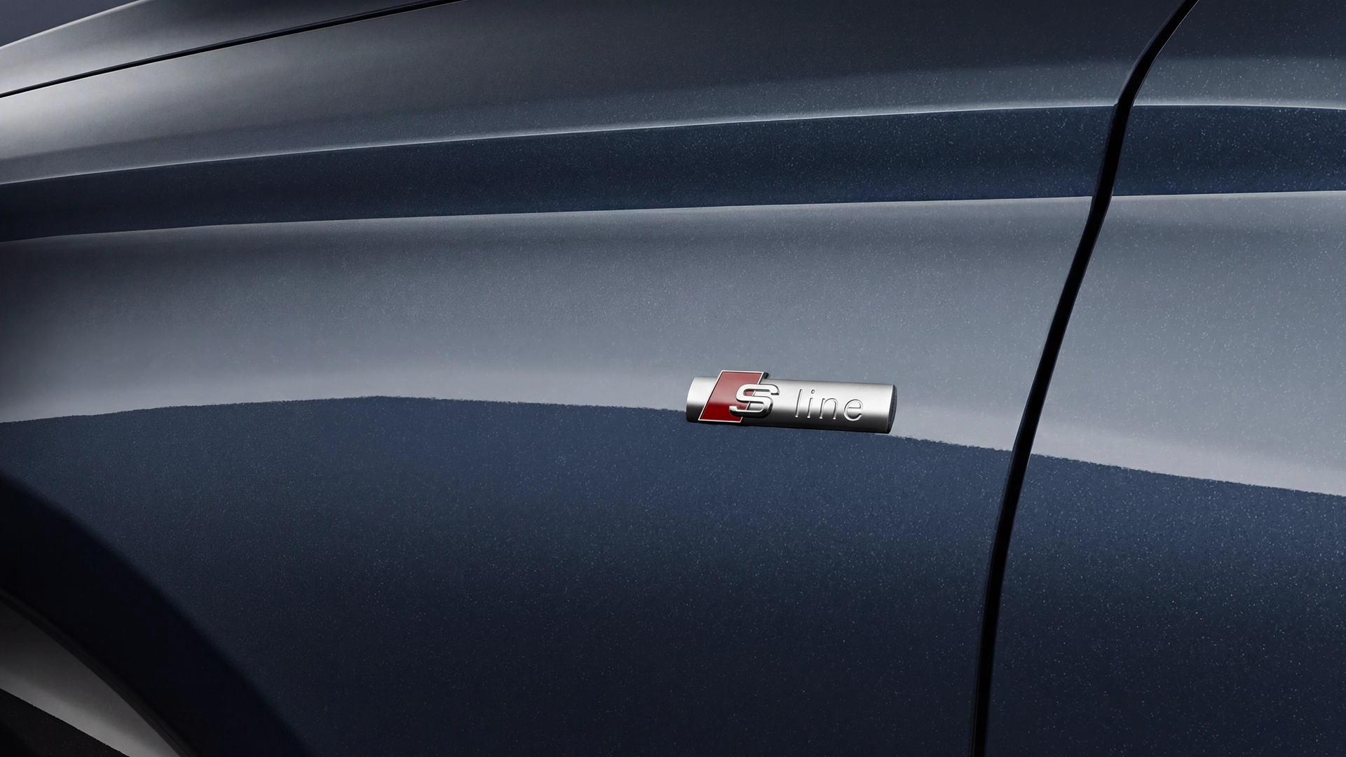 The Q6 SUV e-tron stands sideways on the gravel area in front of a modern house, illuminated by the setting sun.