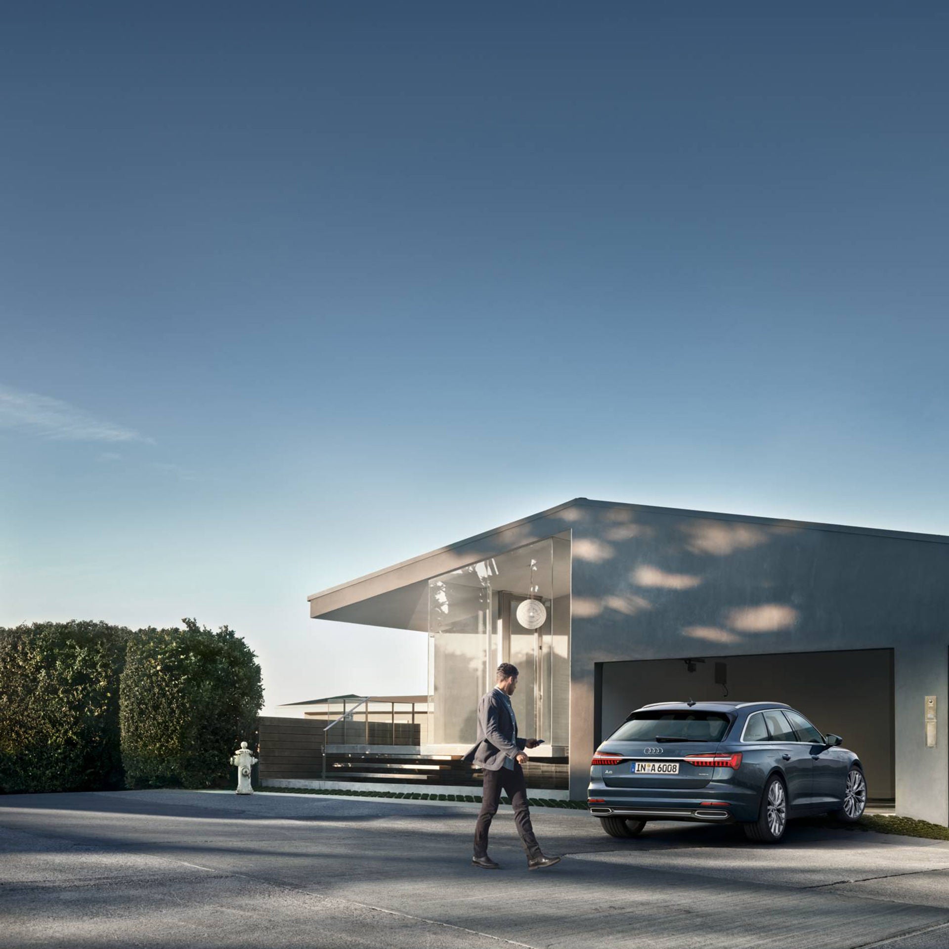  An man i profil som går framför en Audi A6 Avant