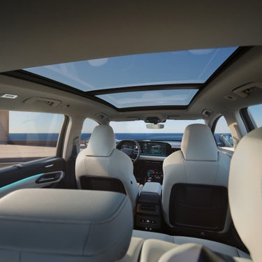 Blick vom Fond auf das Cockpit eines Audi Q6 SUV e-tron mit hellem Interieur und großem Panorama-Glasdach.