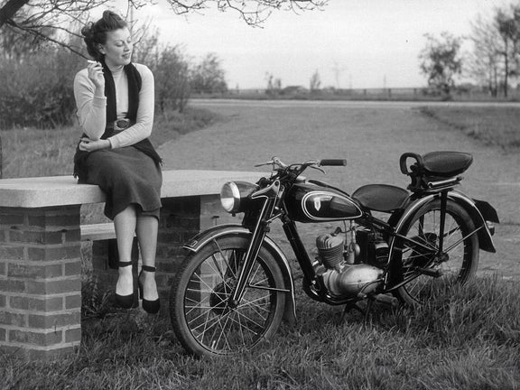 Schwarz-weiß-Aufnahme von einer Frau mit Zigarette neben einer DKW RT 125 W