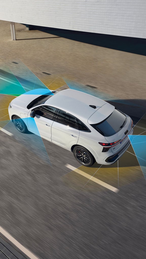 A person holding a smartphone with car control app before two parked Audi cars