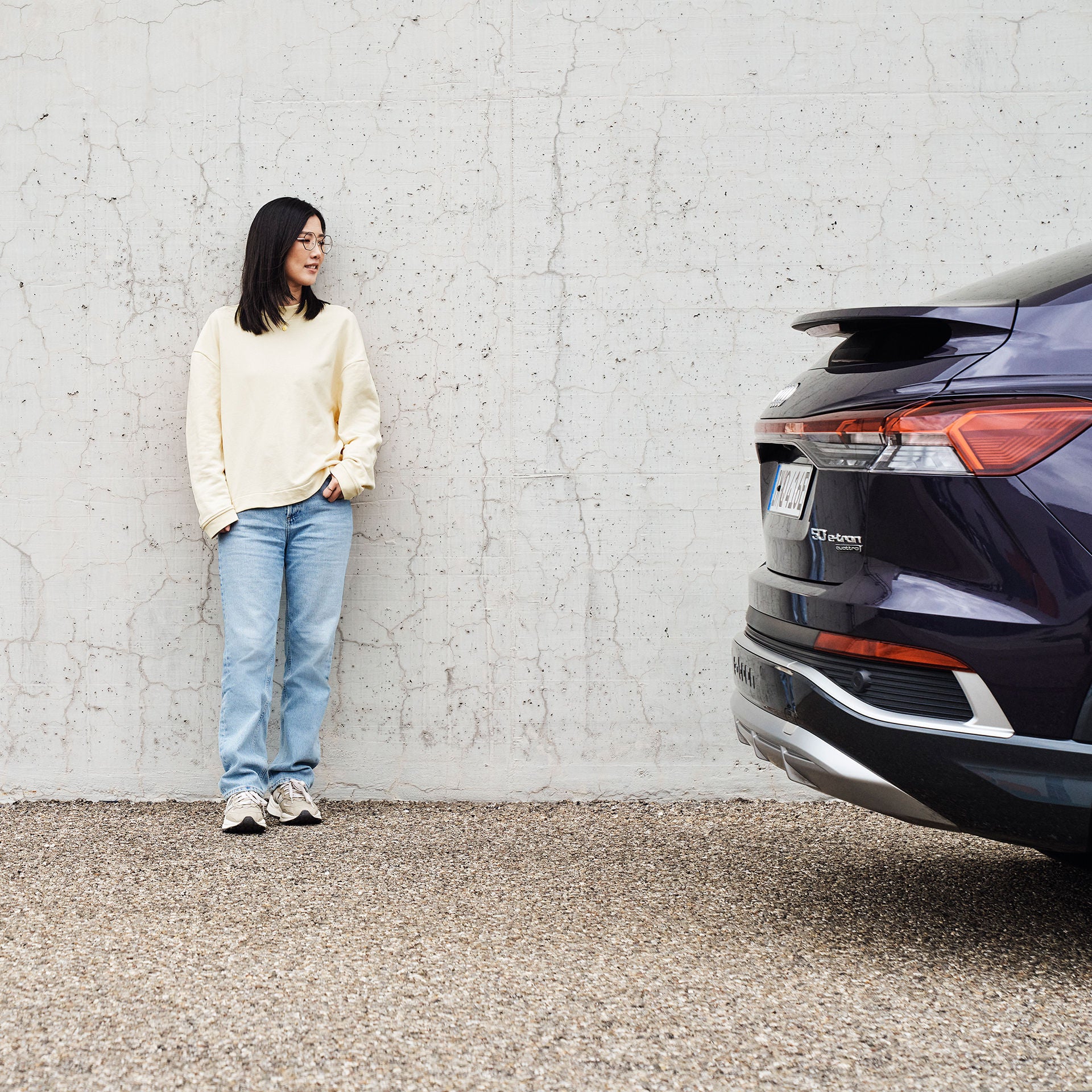 Tiantian schaut auf einen lilanen Audi und ist an eine Wand gelehnt