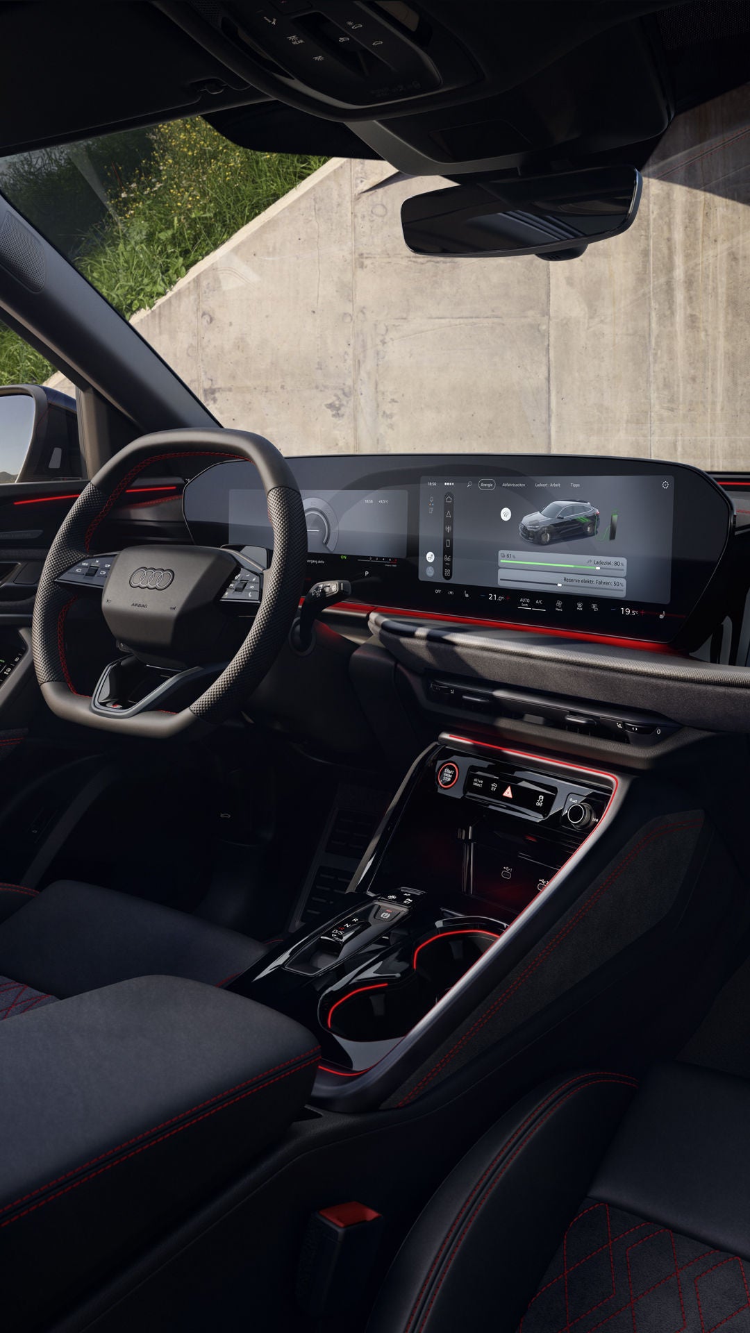 Der Innenraum des Q5 Sportback e-hybrid mit Fokus auf das Lenkrad und die digitalen Displays. Vor dem Fahrzeug steht eine modisch gekleidete, junge Frau.