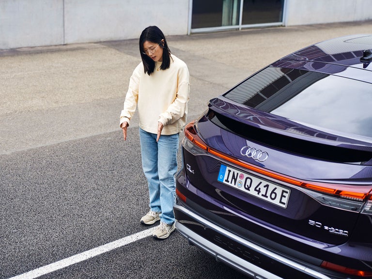 Tiantian explains something and stands next to a purple Audi