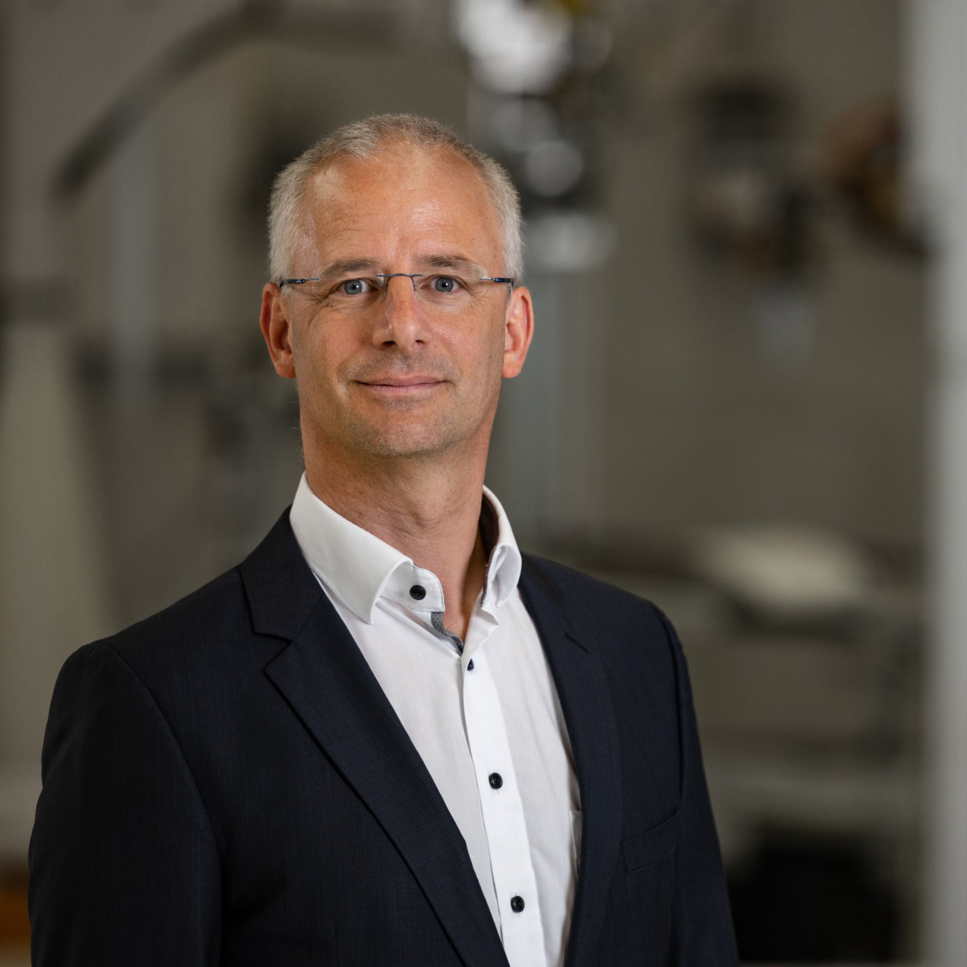 Henning Löser im dunklen Jacket und weißem Hemd lächelt freundlich