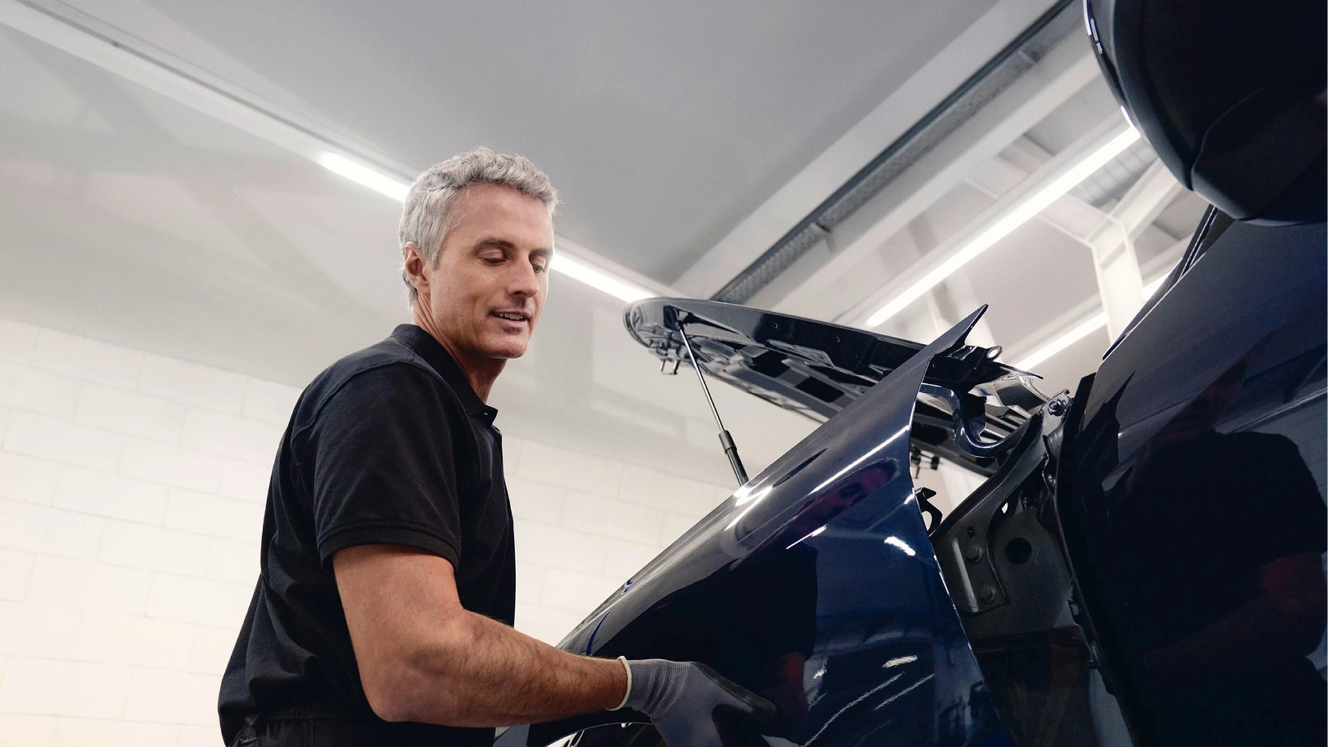 Technician carrying out repairs on the rear body panel of an Audi vehicle in a workshop environment.