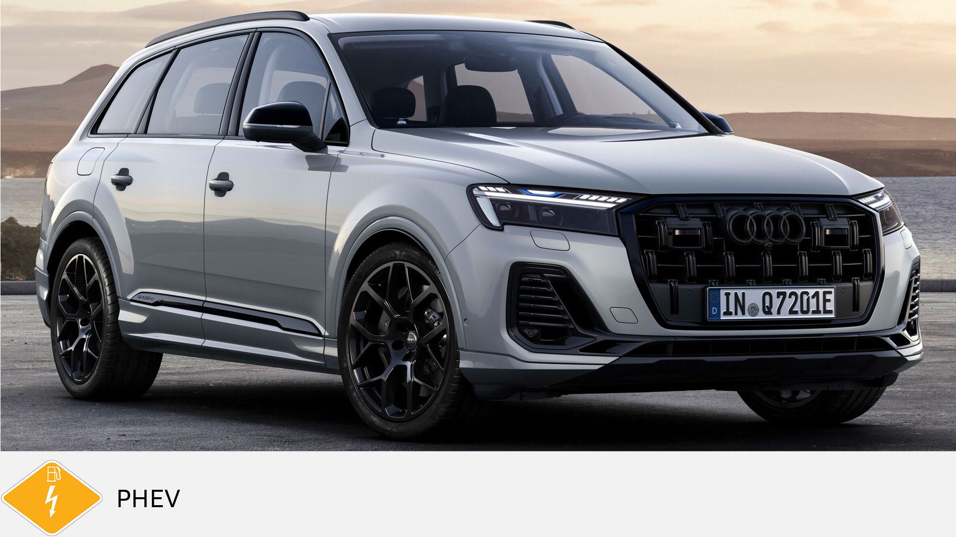 Light gray Audi Q7 TFSI e standing on a coastal road at sunrise. Yellow PHEV symbol with petrol pump below.