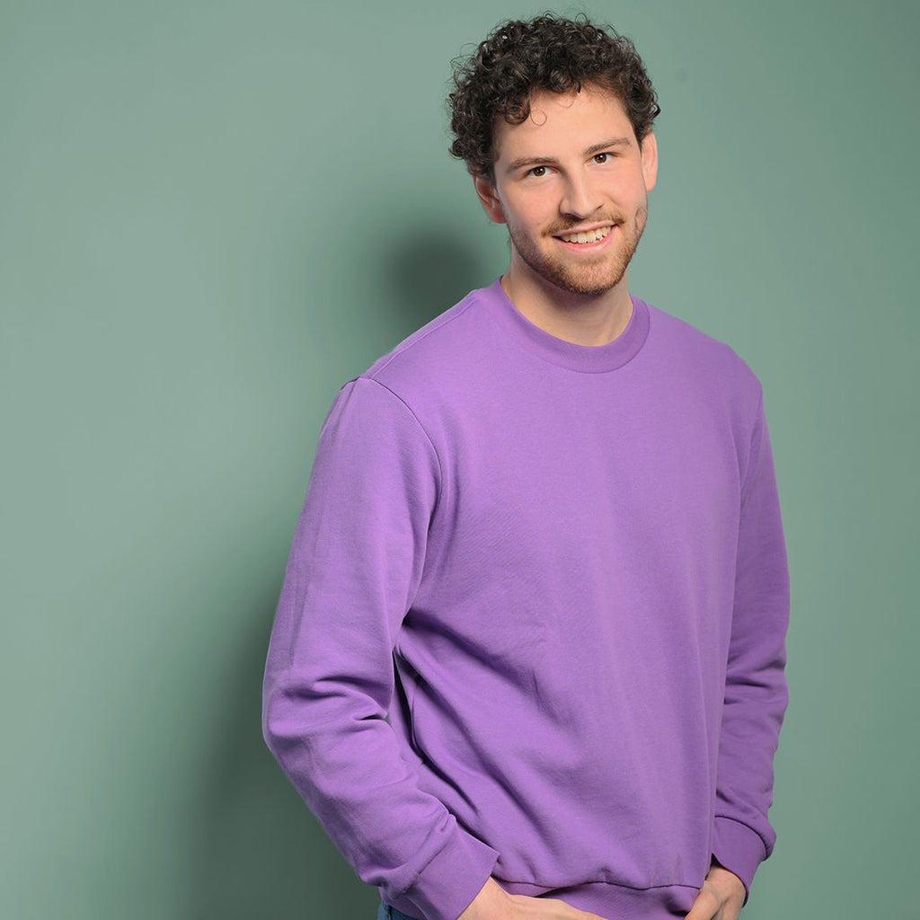 Fabian lächelt in die Kamera und hat seine Hände in den Hosentaschen