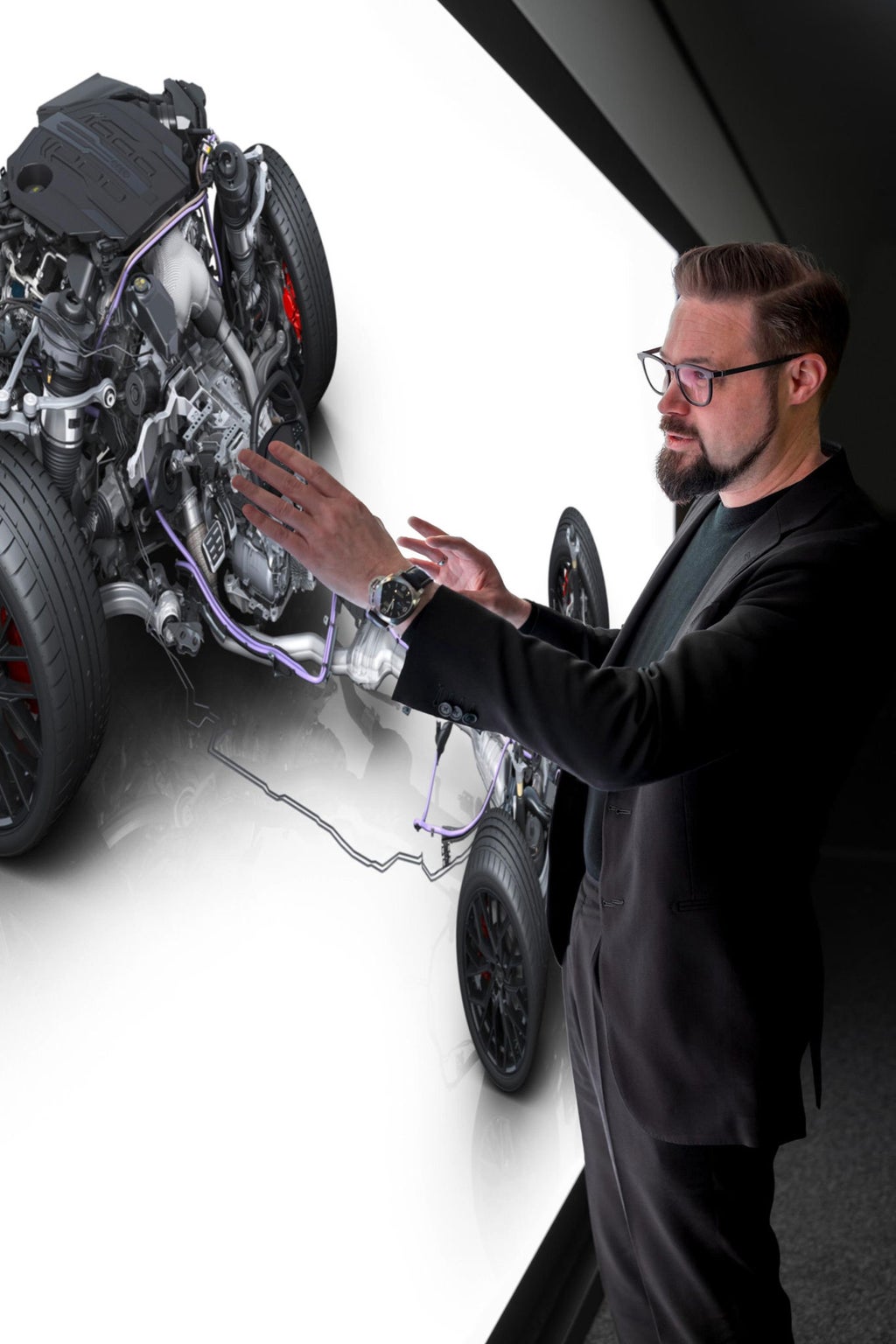 Eine Projektion an einer Powerwall zeigt schematisch den Antriebsstrang eines Audi A6. Matthias Honzen steht davor
und erklärt gestenhaft.