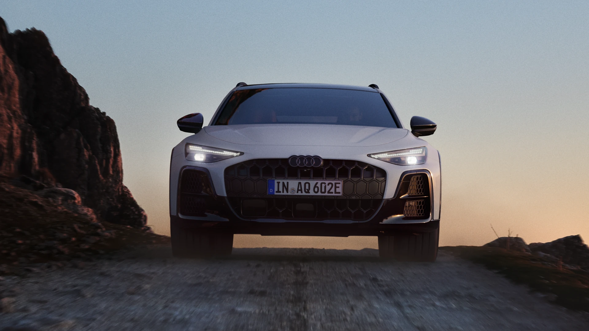 Grey Audi {Model Name} facing front, parked on tarmac in front of building with patterned facade.