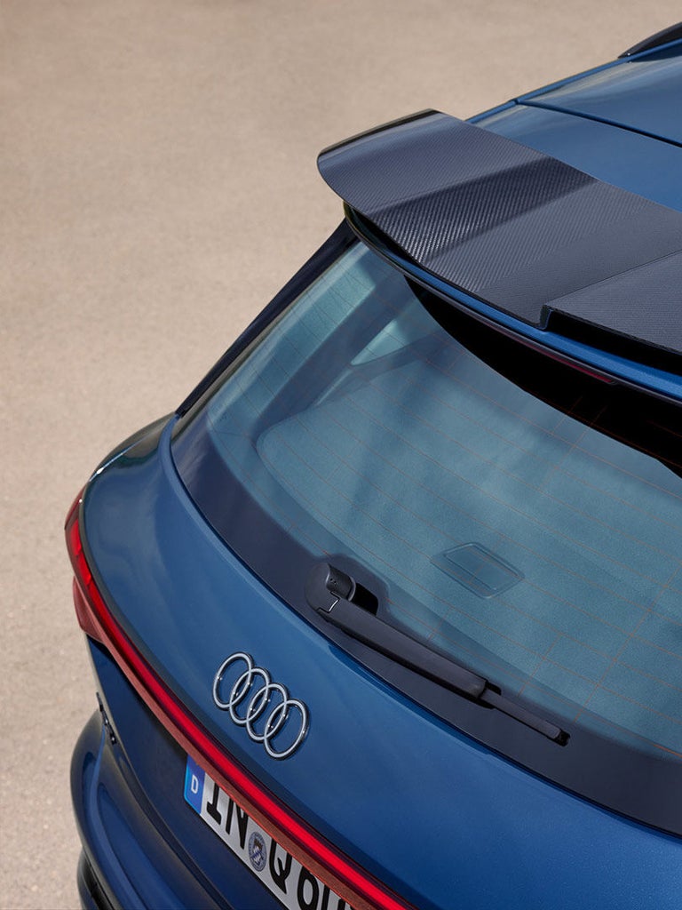 Nahaufnahme eines Carbon-Dachspoilers auf einem blauen Audi Q6 SUV e-tron, mit Antenne und Heckscheibe im Bild.