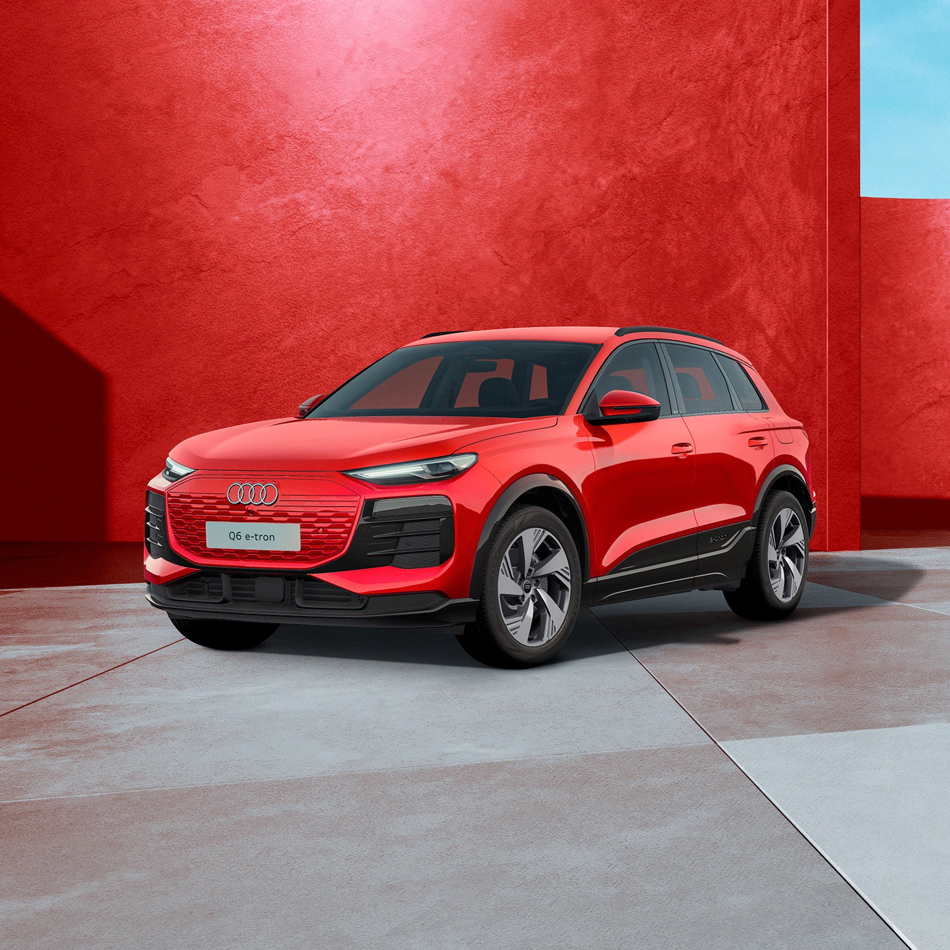 Ein roter Audi Q6 SUV e-tron von schräg vorne fotografiert vor einer modernen Kulisse.