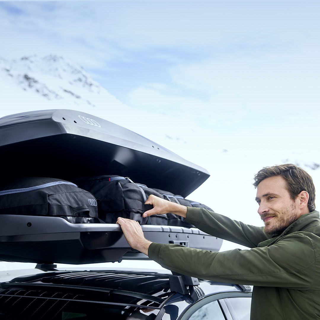 Vista di un veicolo Audi parcheggiato con un capiente box da tetto nero installato sulle barre portatutto. 