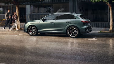 Audi Q3 SUV side view with two people walking towards the car.