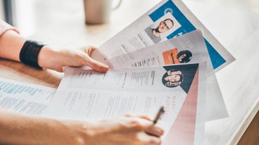 Jemand hält verschiedene Bewerbungen in der Hand und macht sich dazu Notizen