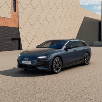 Ein graublauer A6 Avant e-tron von schräg vorne fotografiert vor einer modernen Kulisse.