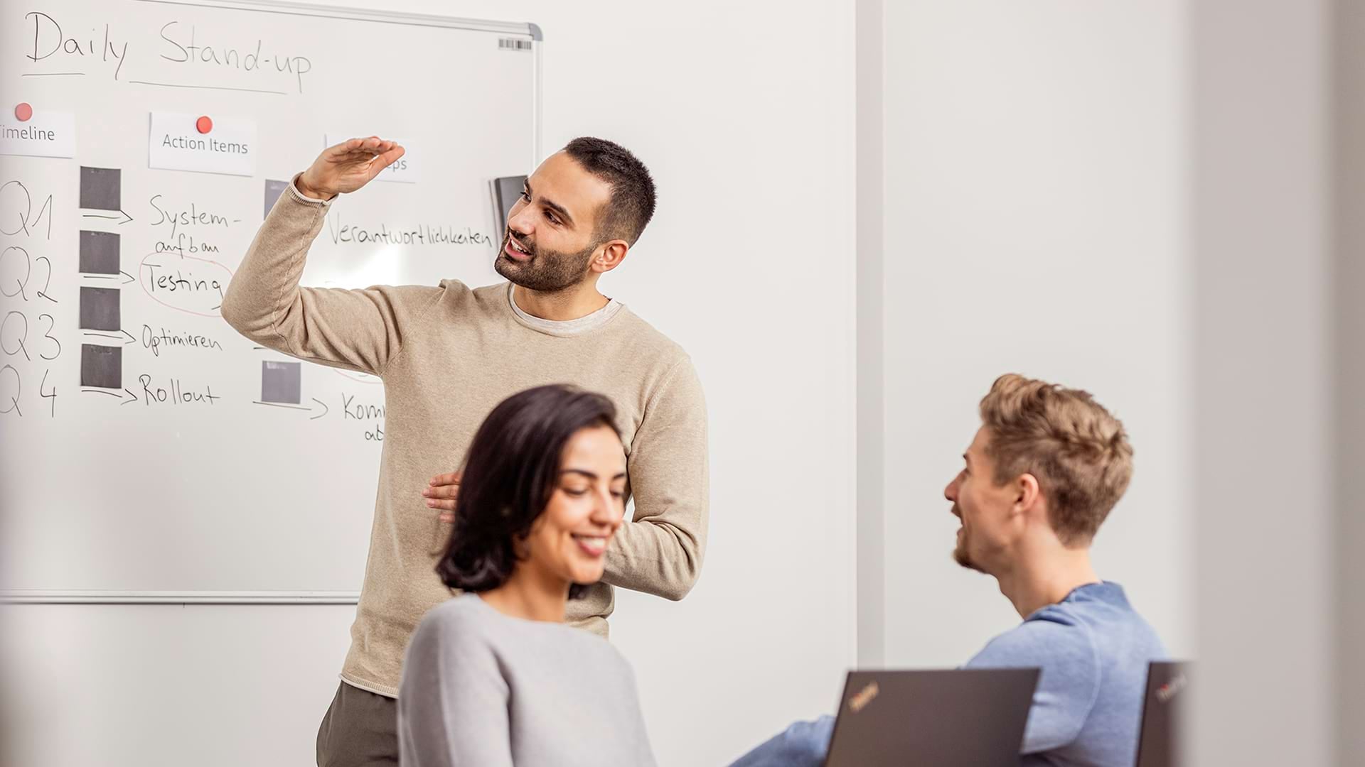 A woman seen from behind is sitting in an Audi model, holding the steering wheel with both hands and driving on a road