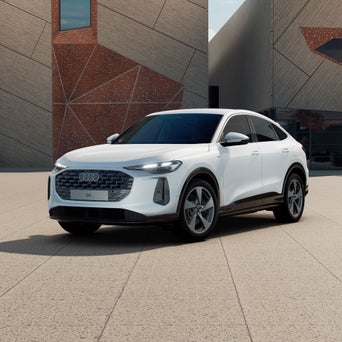 Ein weißer A5 Avant e-hybrid steht vor einem weißen Gebäude