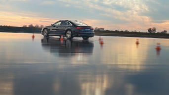 Black A8 50 TDI quattro on a wet track with a course, with dusk in the background.