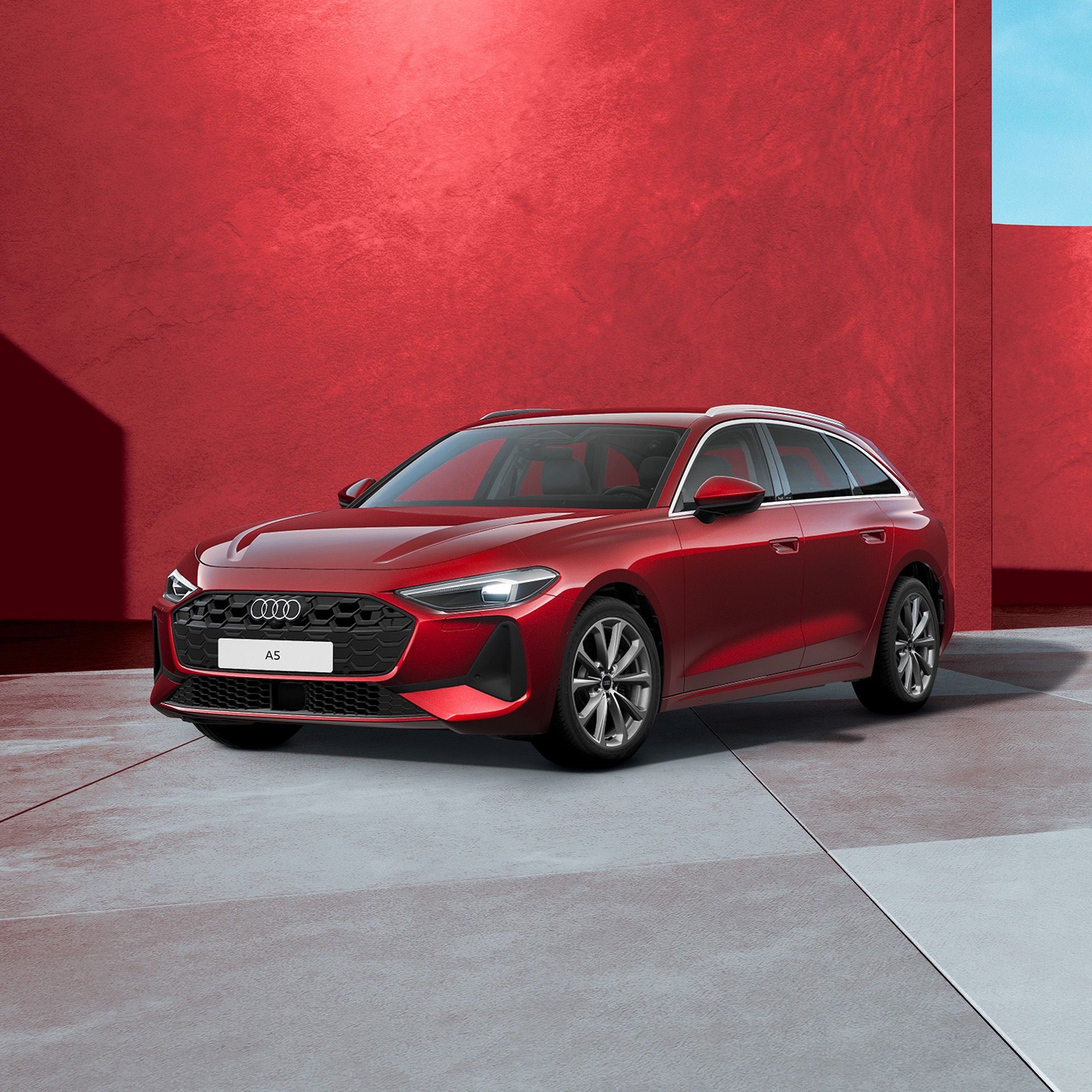 Ein roter Audi A5 Avant von schräg vorne fotografiert vor einer modernen Kulisse.