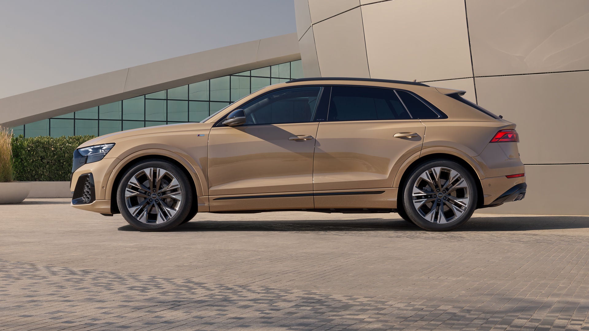 Der Q8 SUV von der Seite, parkend vor einem futuristischem Gebäude.