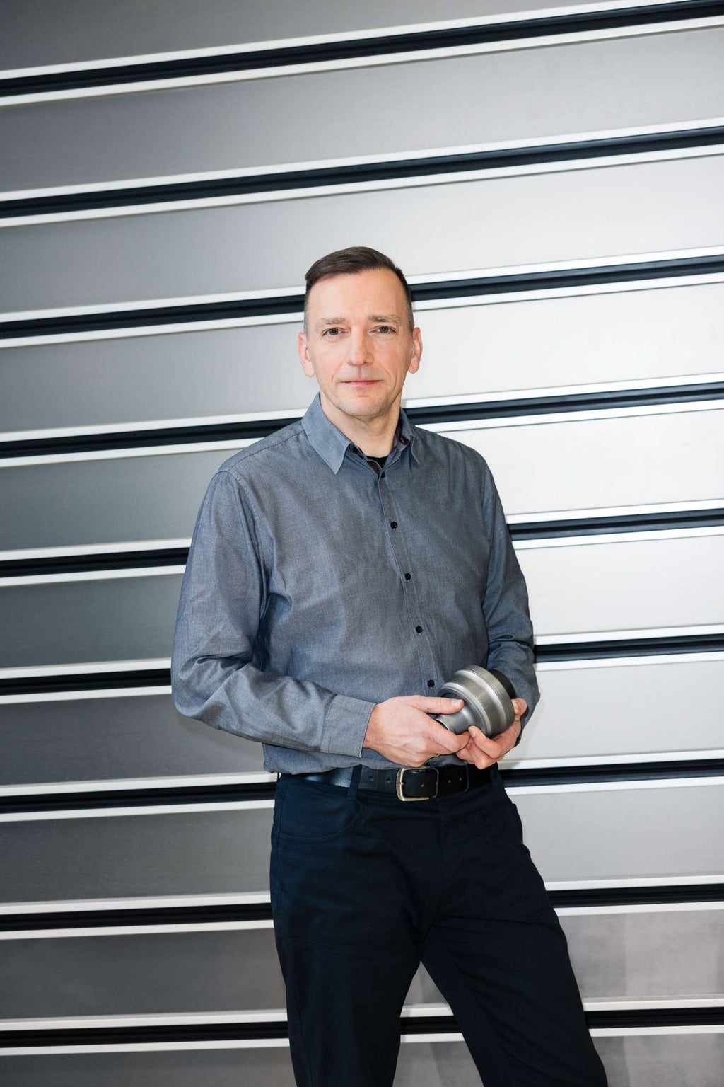 Dieter Weidemann steht vor einem Rolltor und hält ein Mittendifferenzial in den Händen.