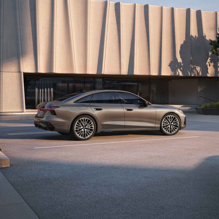 Eine Audi A6 Limousine fährt auf der Straße im sportlichen Design bei Sonnenuntergang.