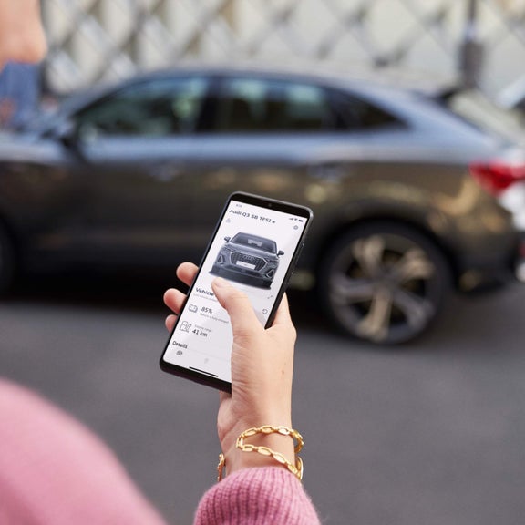 Lady using Audi mobile app close to Audi Q3.