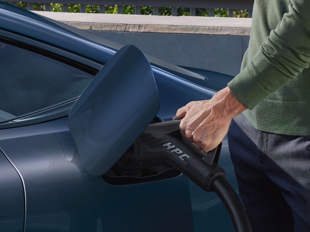 Close-up van de laadconnector op de A6 Sportback e-tron. Een man sluit een laadkabel aan.