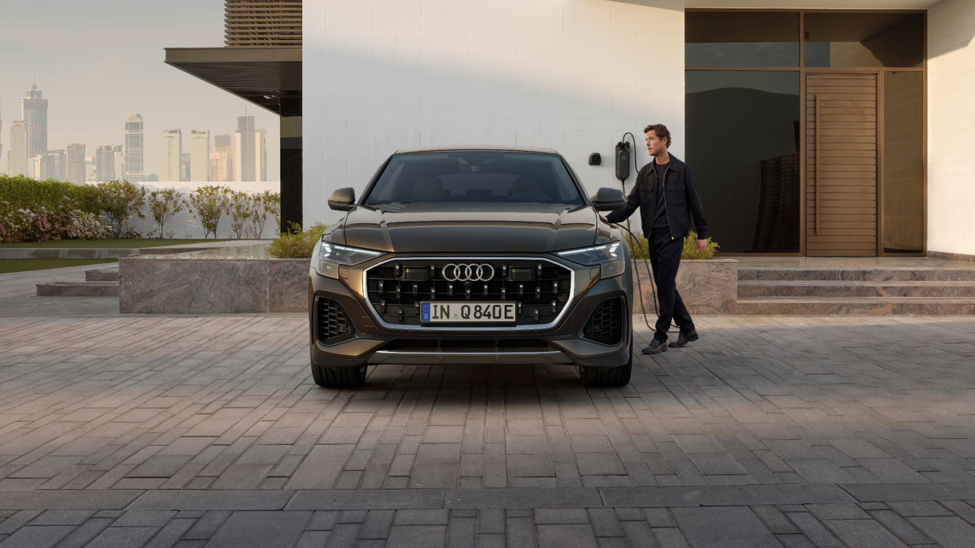 Q8 TFSI e står parkerad framför ett hus, en person är påväg att öppna dörren vid förarsidan.