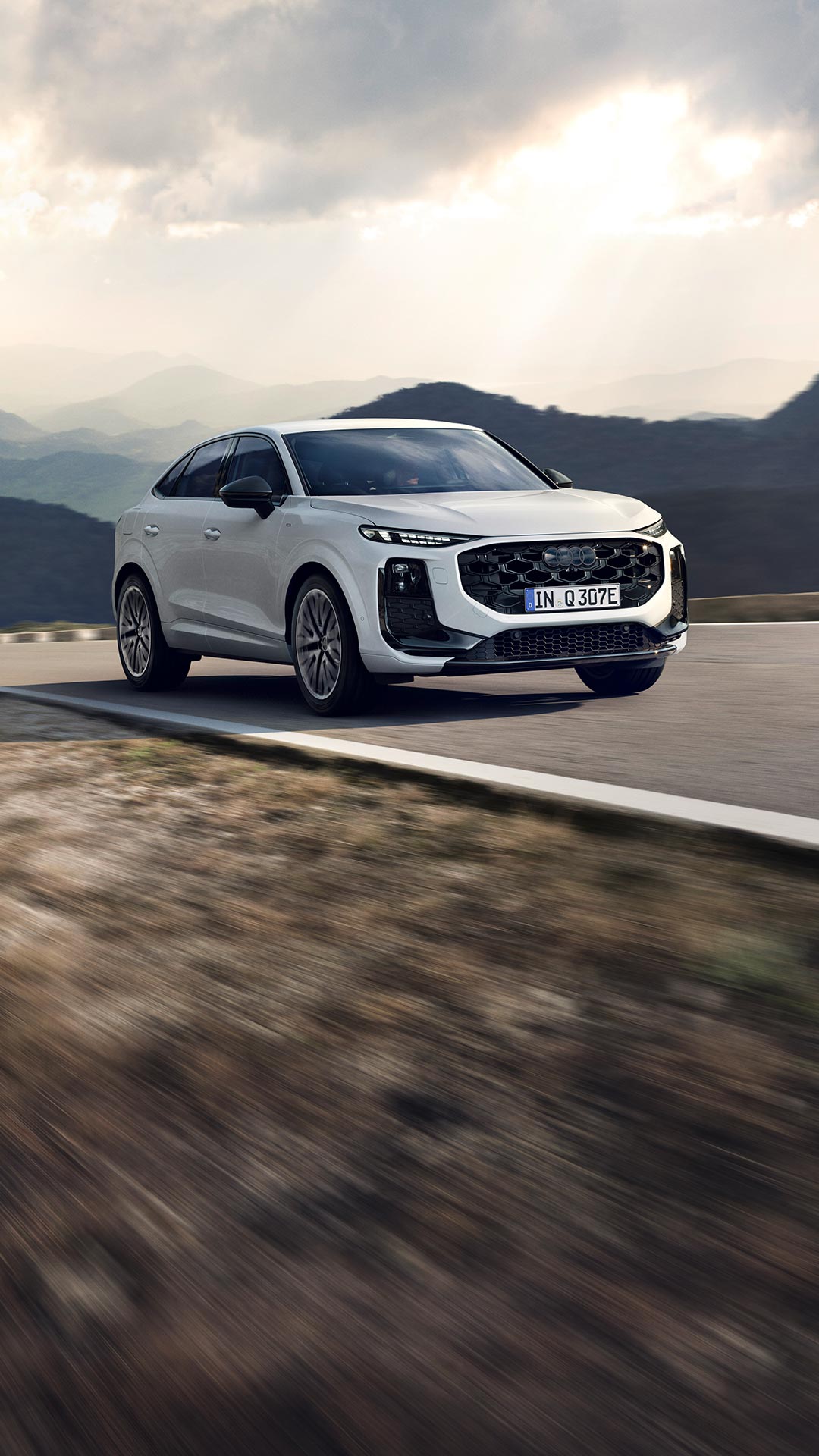 Un’Audi Q3 Sportback e-hybrid bianca in marcia su una strada di montagna 