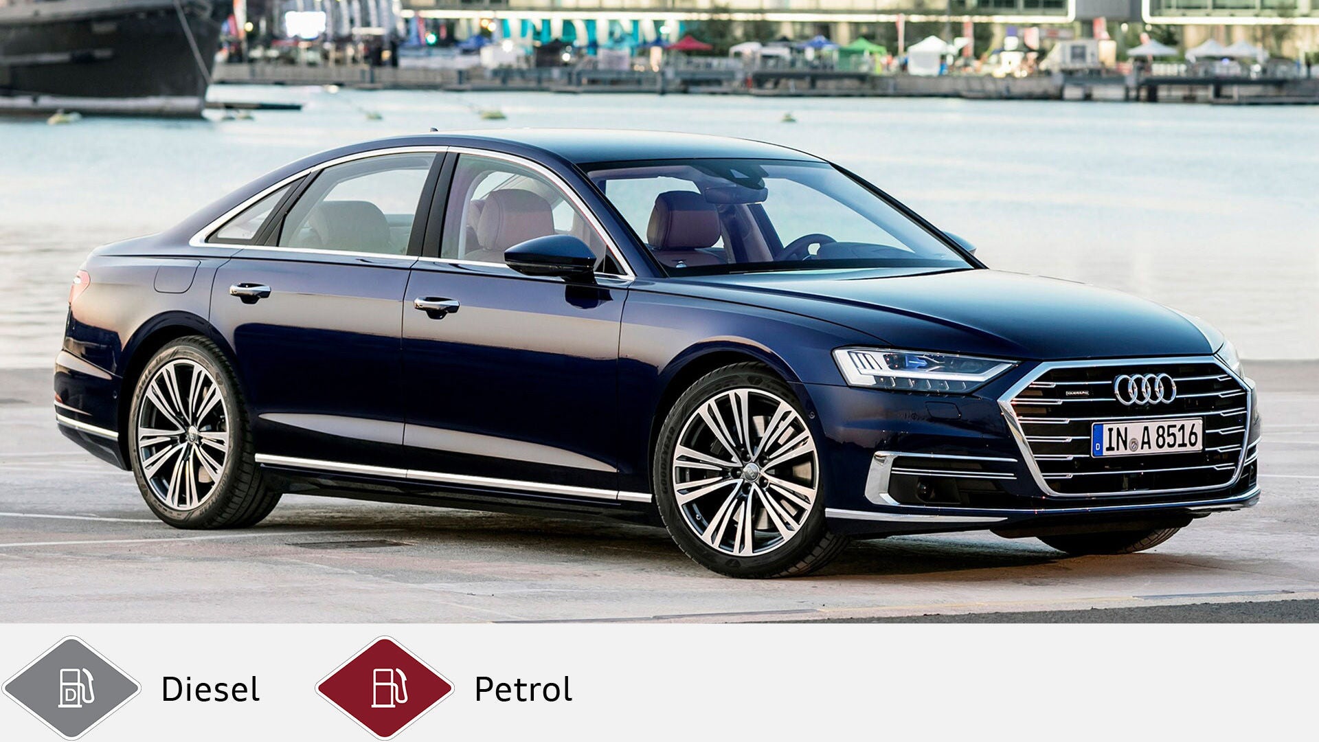 Blue Audi A8 parked at the side of a harbor basin with water and buildings in the background. Below gray diesel symbol and red gasoline symbol.
