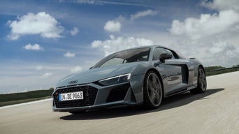 Matt gray Audi R8 Coupé V10 performance quattro on a race track under a blue sky with a few light cloud