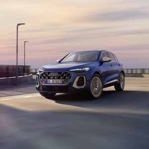 Der SQ5 SUV in dunkelblau fährt über eine Brücke. Am Steuer befindet sich eine junge Frau.&nbsp;