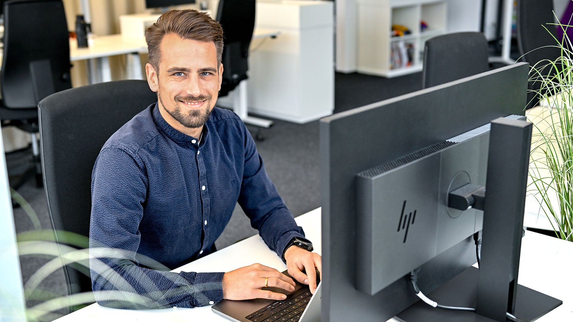 Markus, Product Manager SCD, sits at his laptop and laughs into the camera
