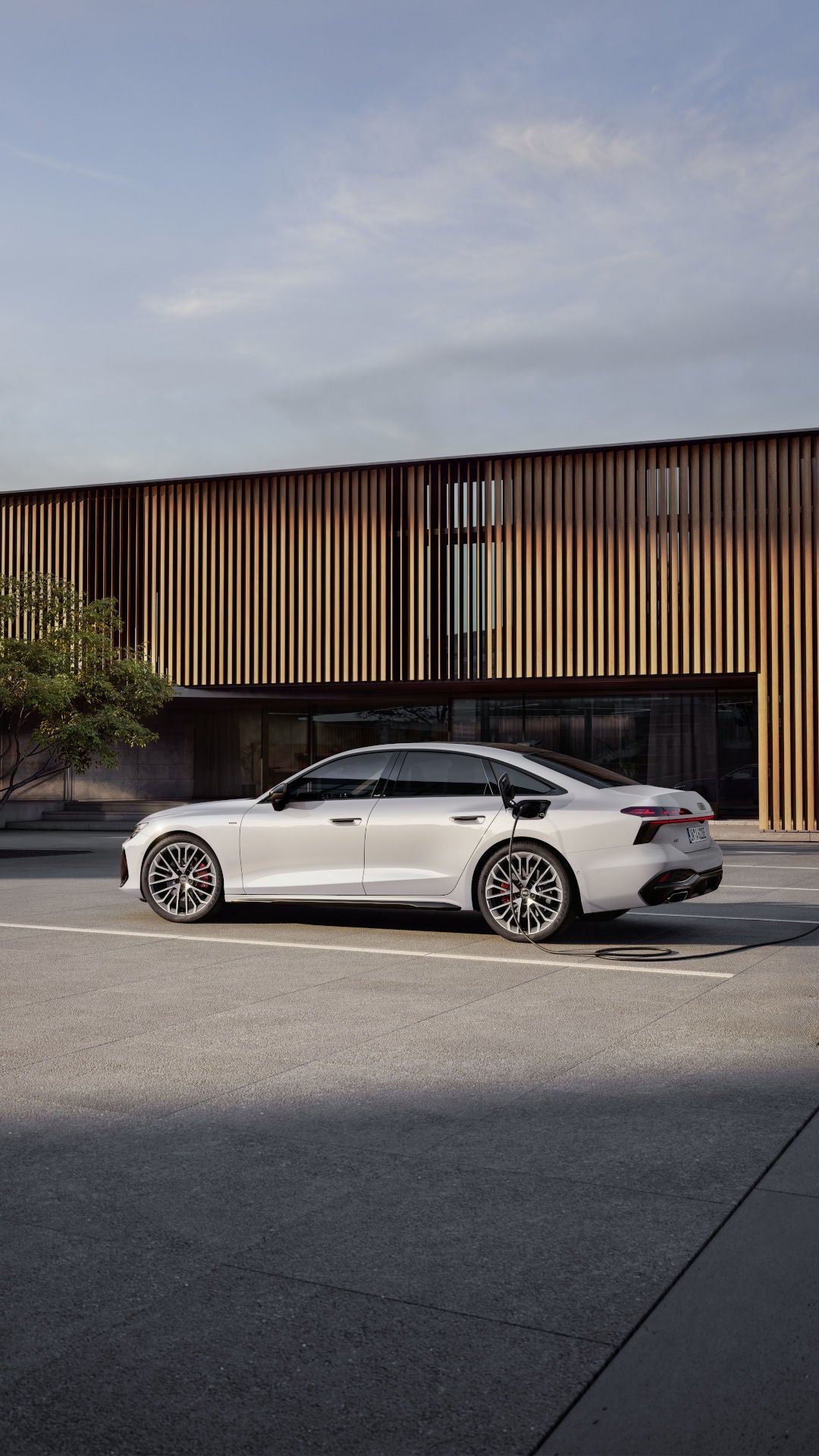 De Audi A6 Limousine e-hybrid quattro voor een fraai modern houten huis.