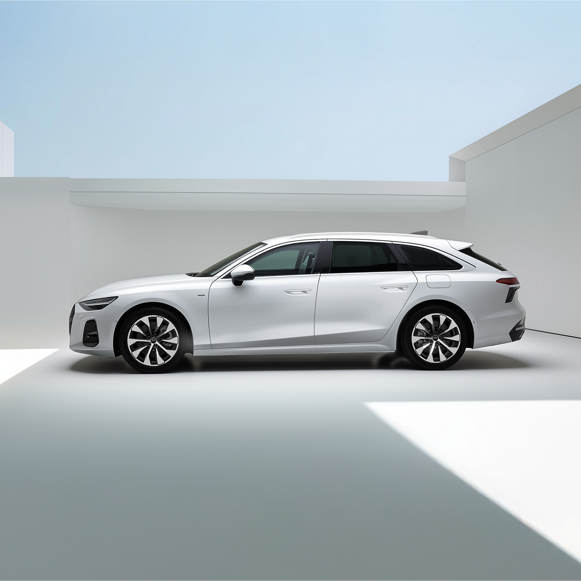 Weißer A6 Avant e-hybrid steht seitlich von hinten vor einer Ladestation