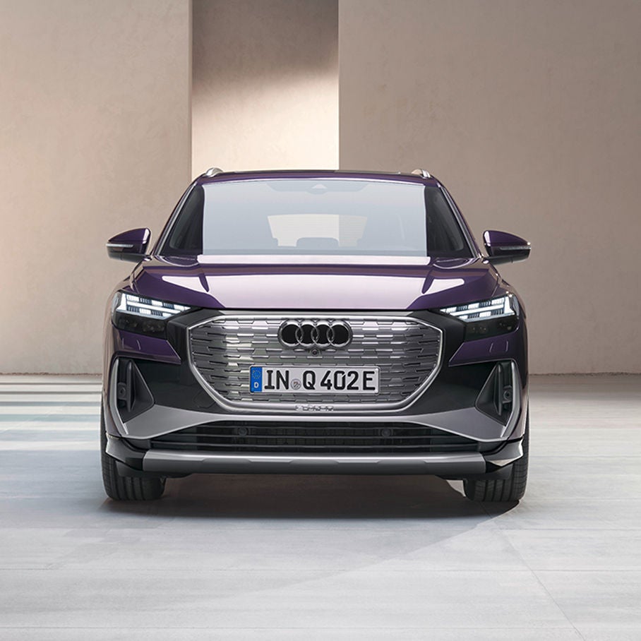 Front view of a purple Audi Q4 e-tron showcasing its sleek design, signature grille, and modern headlights in a minimalist setting.