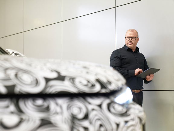 Steffen has an IPad in his hands and looks at an Audi