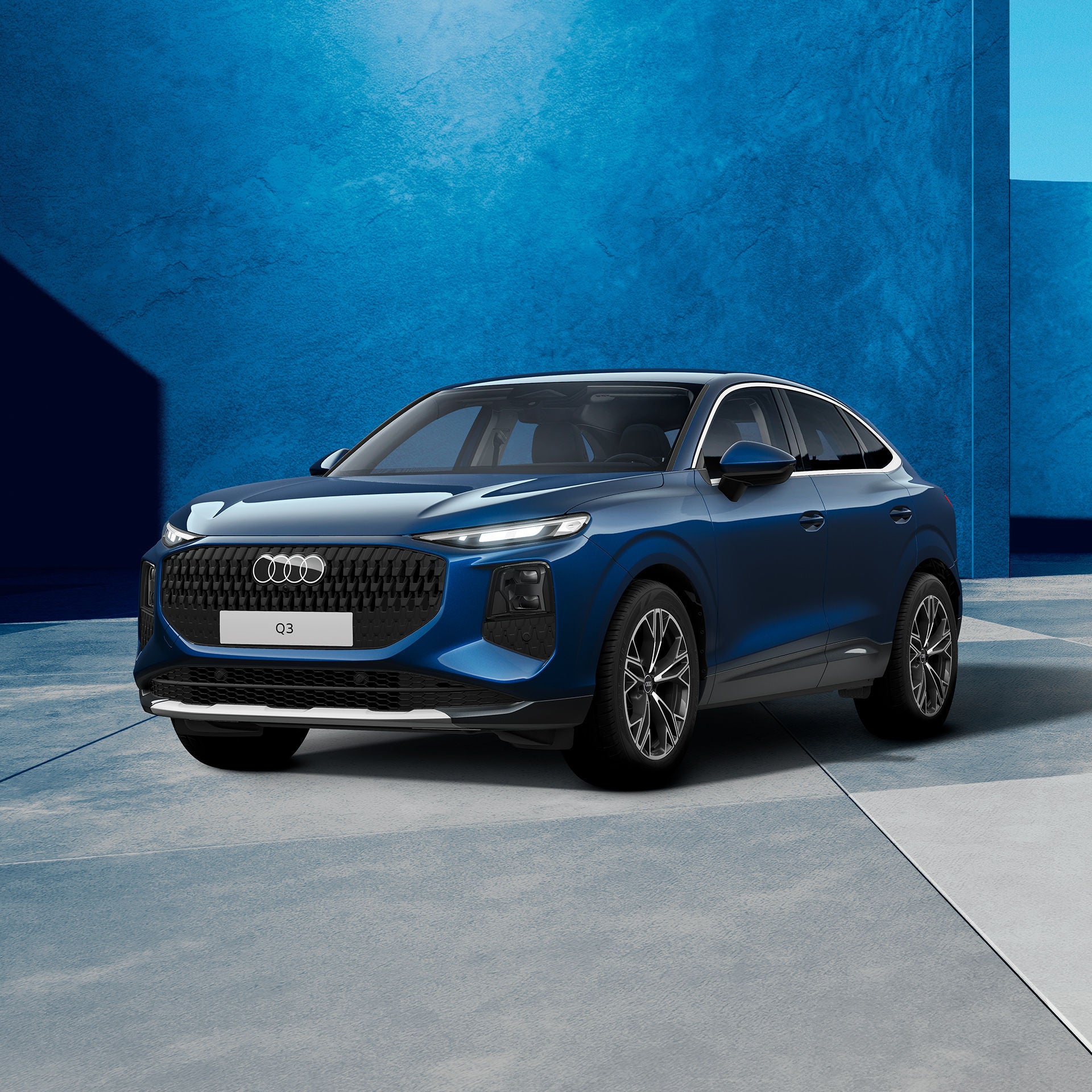 Ein dunkelblauer, moderner SUV steht in einem grauen Studio. Das Fahrzeug ist schräg von vorne zu sehen und wird von weichem Tageslicht beleuchtet.