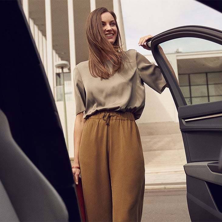 Dame står i døråpning på sin Audi.