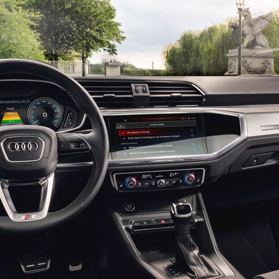 Driver side cockpit view of Audi Q3 with monument visible through car window.