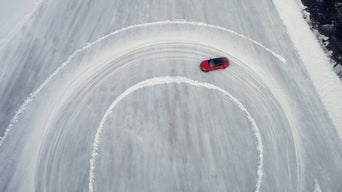 Roter Audi RS e-tron GT performance zieht eine große Kurve auf einer vereisten Fläche, fotografiert aus der Luft.