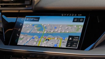 Person im Audi-Innenraum bedient Touchscreen mit Fahrzeugfunktionen, digitales Cockpit und Klimaeinstellungen sichtbar.