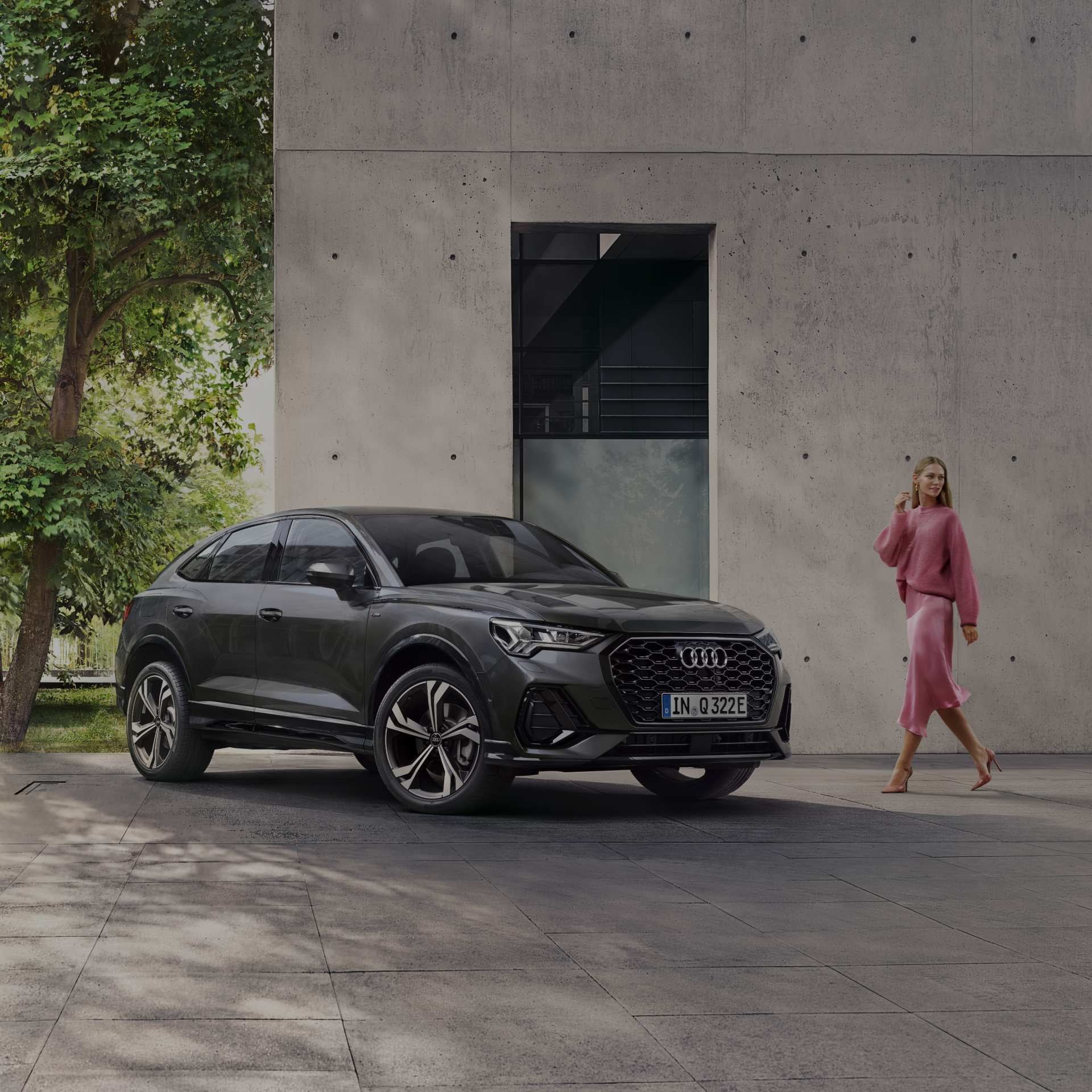 Lady in pink outfit looking over her shoulder approaching carbon Audi Q3