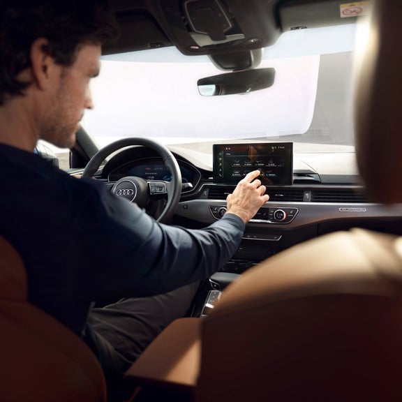 Person in car adjusting touchscreen display on dashboard.