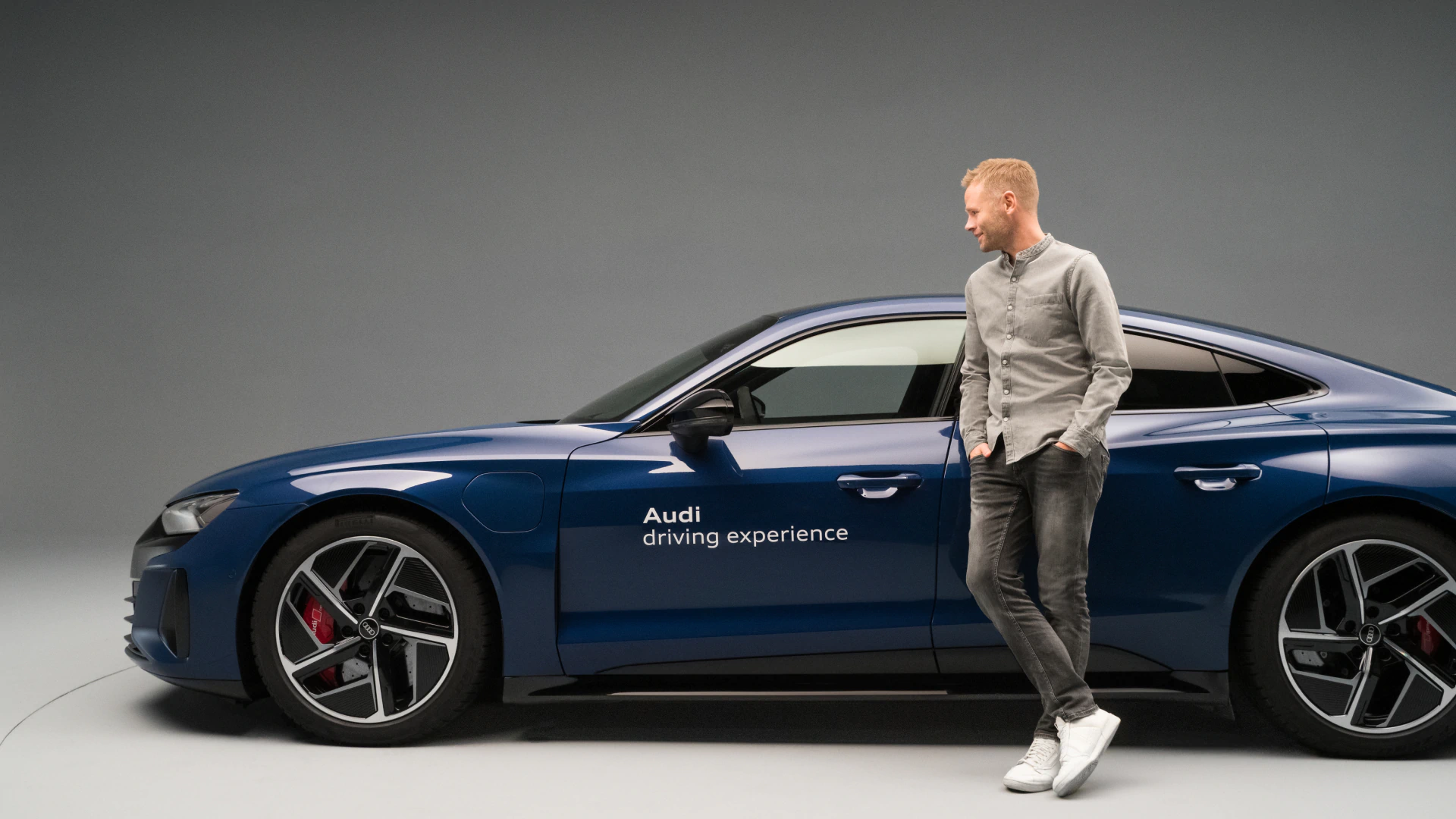 Christopher Broeker leaning against an Audi RS e-tron GT{ft_rs-e-tron-gt} bearing the words “Audi driving experience”.